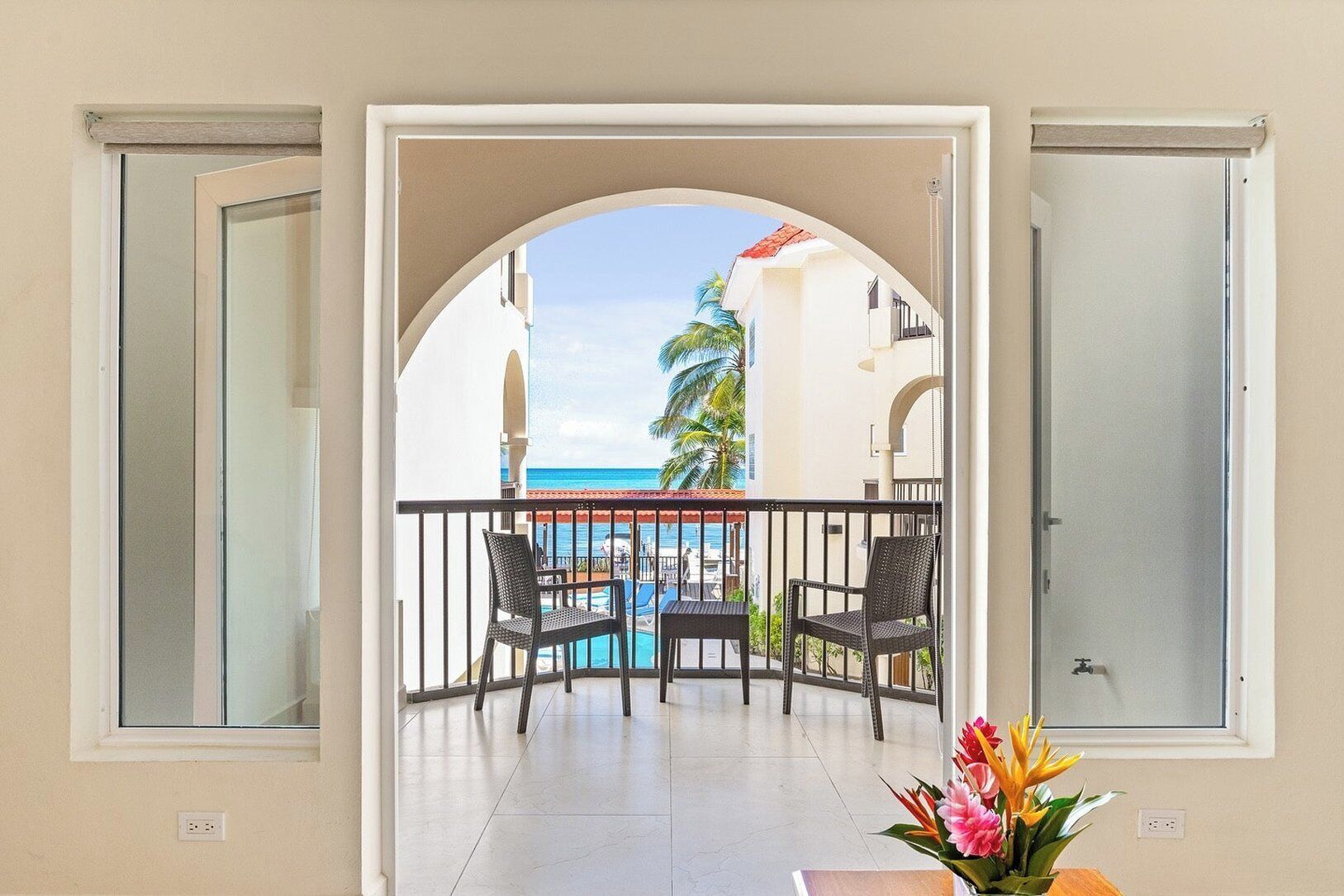 A balcony with a view of a pool and the ocean.