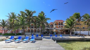 A resort with a wooden deck, palm trees, and a building with a red roof. - Sunbreeze Suites (San Pedro)
