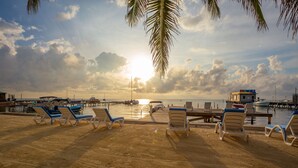 A beach with lounge chairs and a pier. - Sunbreeze Suites (San Pedro)