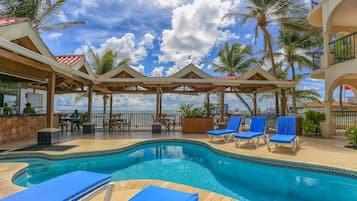 Una piscina al aire libre, sillones reclinables de piscina