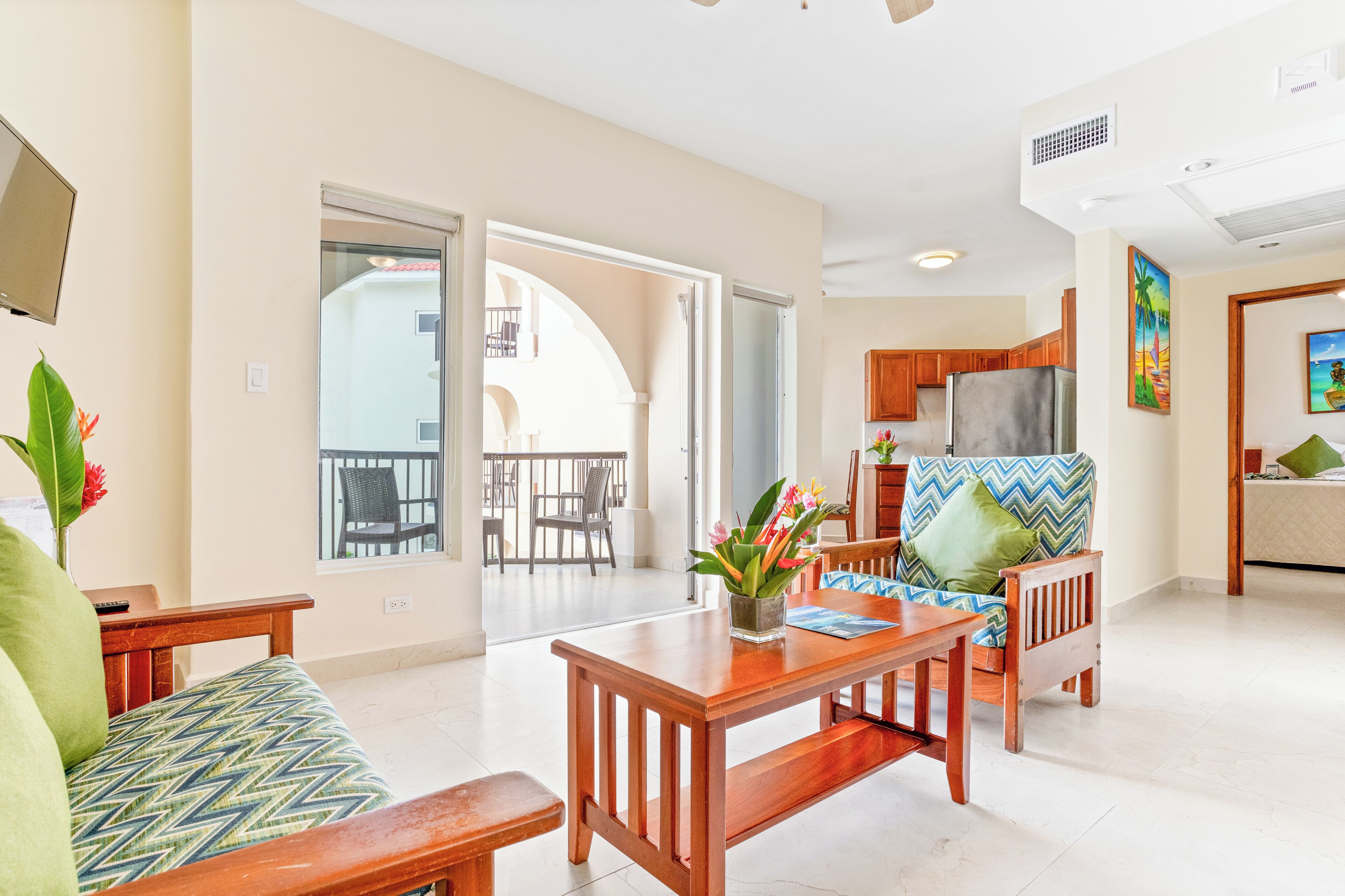 A spacious living area with a wooden dining table, a sofa, and a balcony with a view.