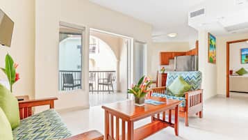 A spacious living area with a wooden dining table, a sofa, and a balcony with a view.