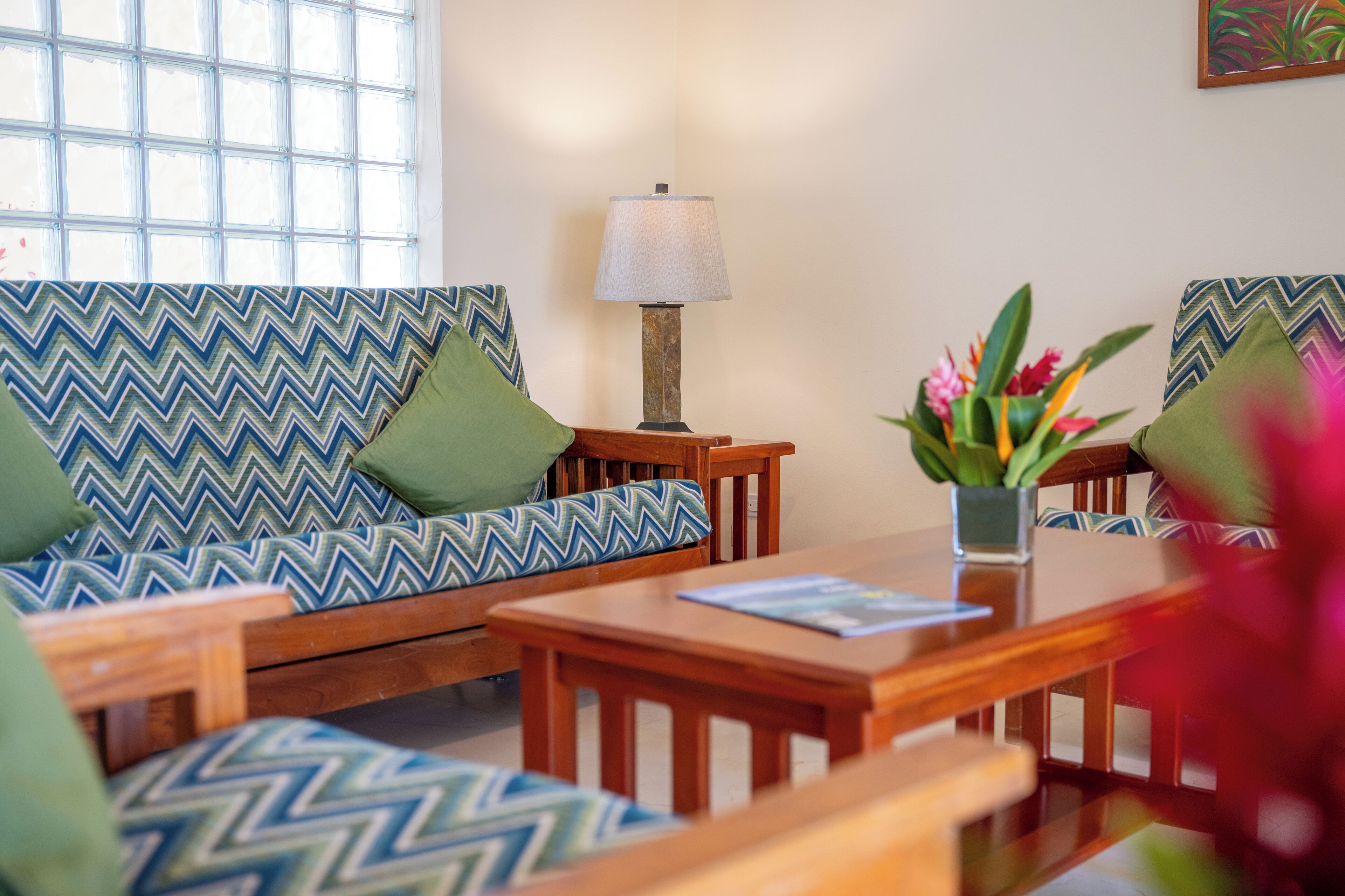 A living room with a sofa, armchairs, a coffee table, and a lamp.