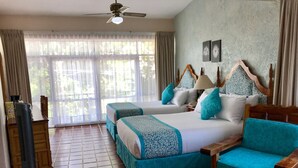 A hotel room with two beds, a wooden chair, a ceiling fan, and a large window with curtains. - Hotel Quinta Las Flores (Cuernavaca)