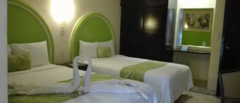 A hotel room with two beds, each with a green headboard and white bedding. There is a mirror on the wall and a chair in the corner.