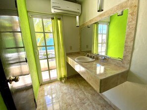 A bathroom with a sink, mirror, and a window with curtains.