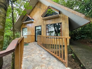 A wooden cabin with a stone pathway leading to the entrance, surrounded by trees. - Arenal Waterfall Lodge Villas (La Fortuna)