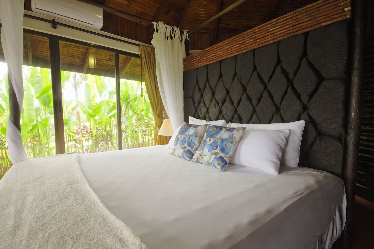 A bed with a tufted headboard, white bedding, and blue patterned pillows.