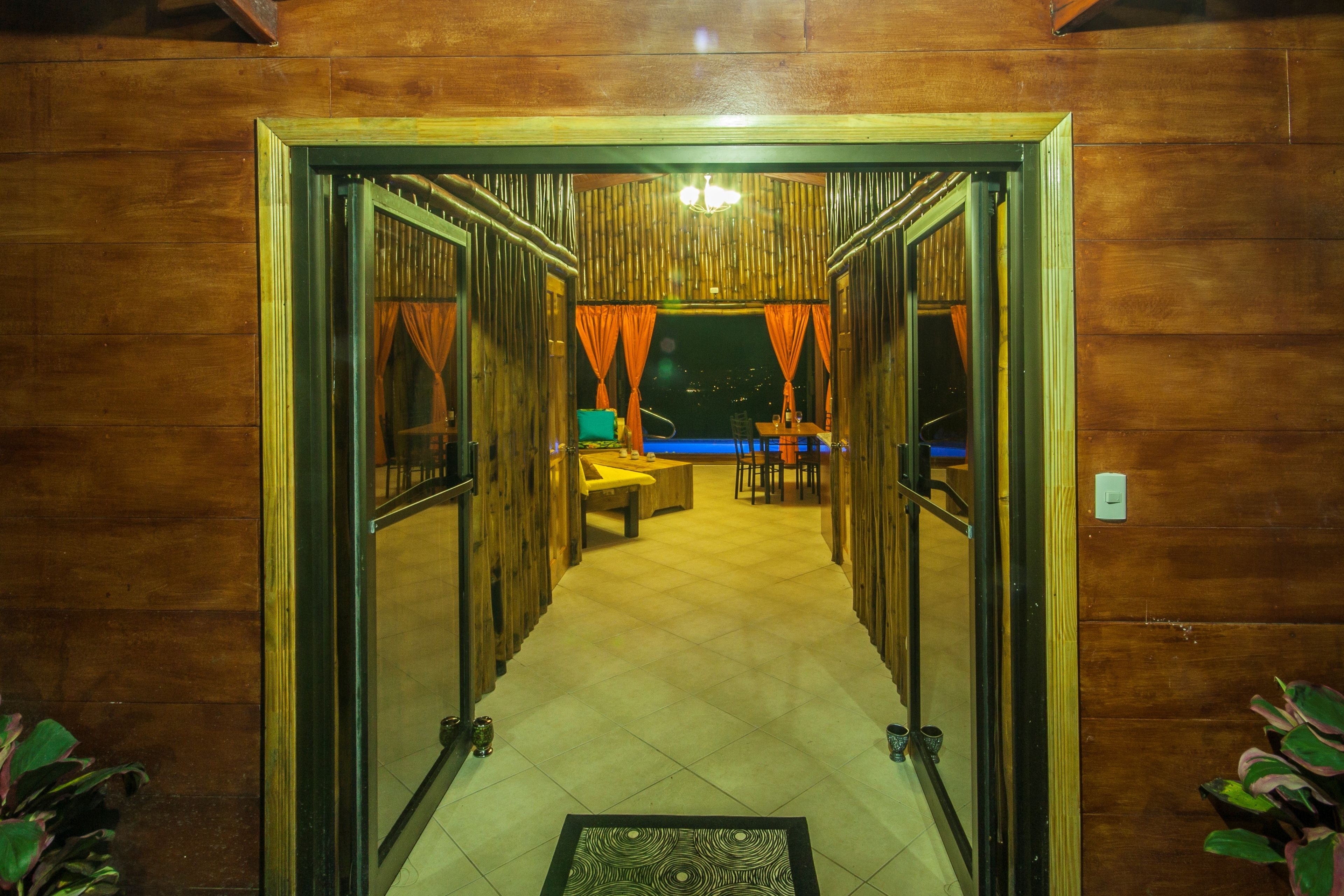 A wooden interior hallway leading to a dining area with a pool view.