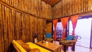 Ein Zimmer mit Bambuswand, einem gelben Sofa, einem Holztisch und Blick durch eine Glastür.