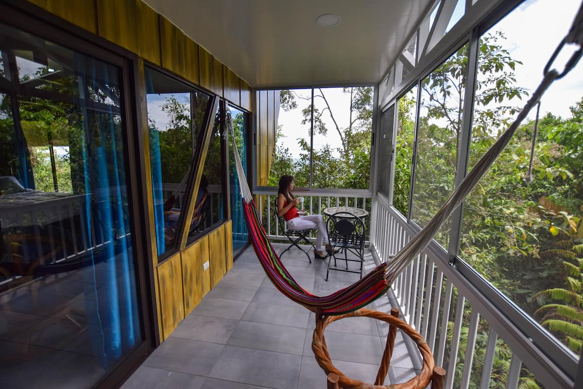 A balcony with a hammock, a table, and chairs.