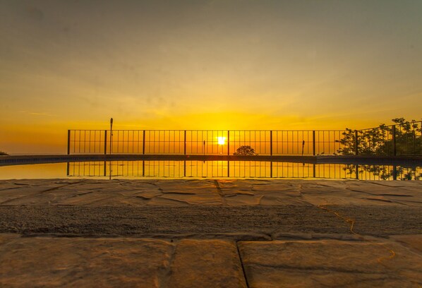 Un atardecer sobre un cuerpo de agua tranquilo con una valla al frente.