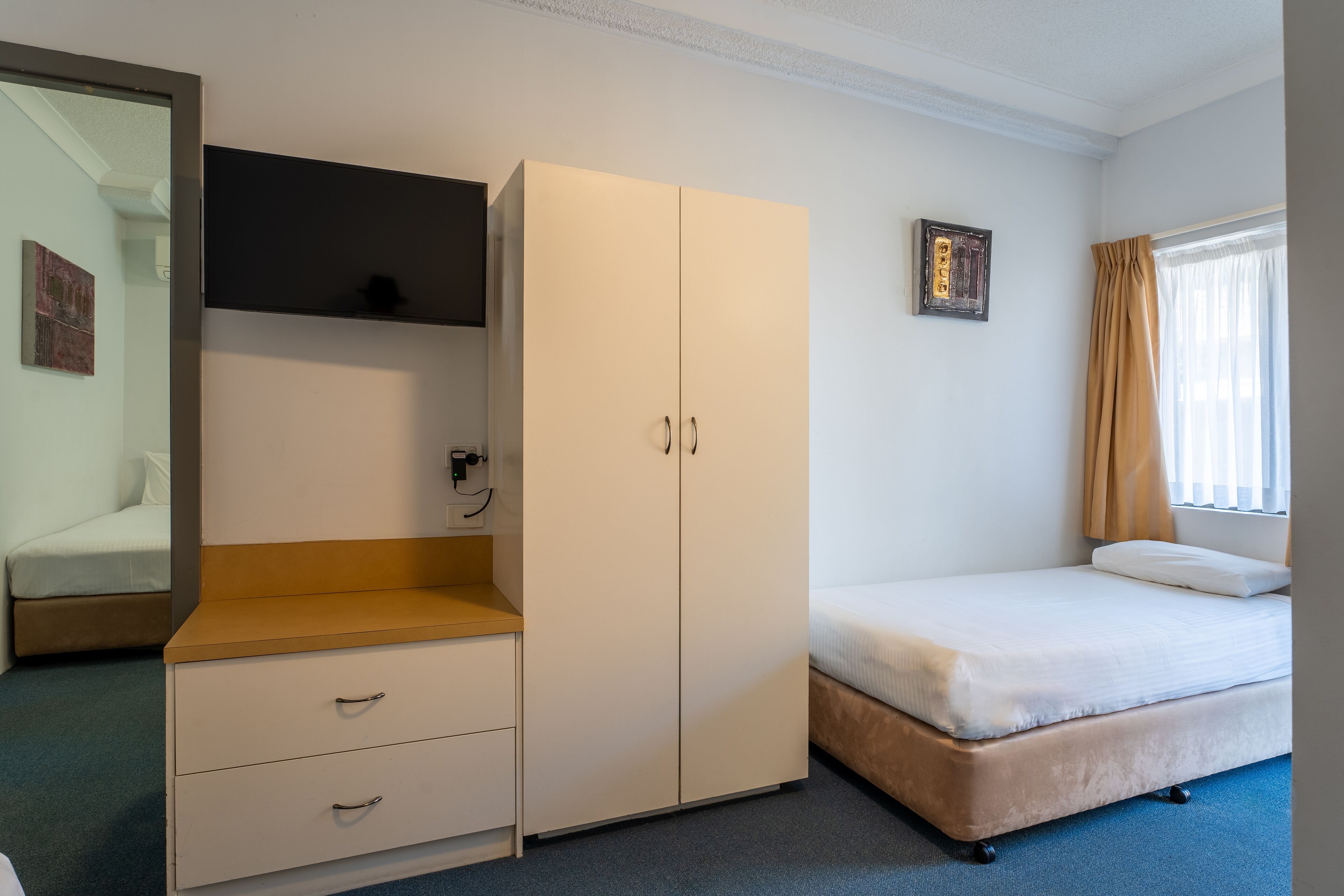 A bedroom with a bed, a wardrobe, a desk, and a mirror.