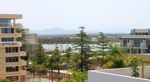 A residential building with multiple floors, a balcony, and a view of a beach and mountains in the distance. - Port Aloha Motel (Port Macquarie)