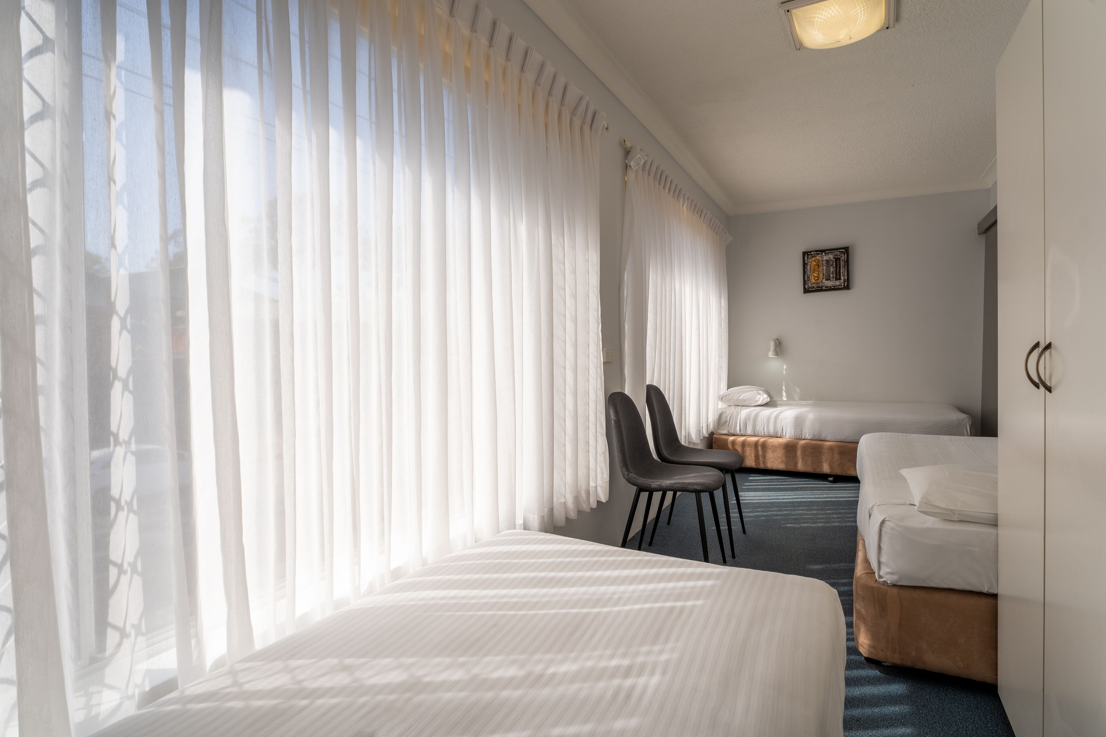 A hotel room with two beds, a desk, and a chair.