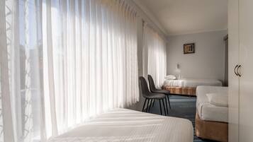 A hotel room with two beds, a desk, and a chair.