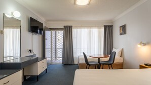 A hotel room with a bed, a desk with a chair, a mirror, a TV, and a window with curtains. - Port Aloha Motel (Port Macquarie)