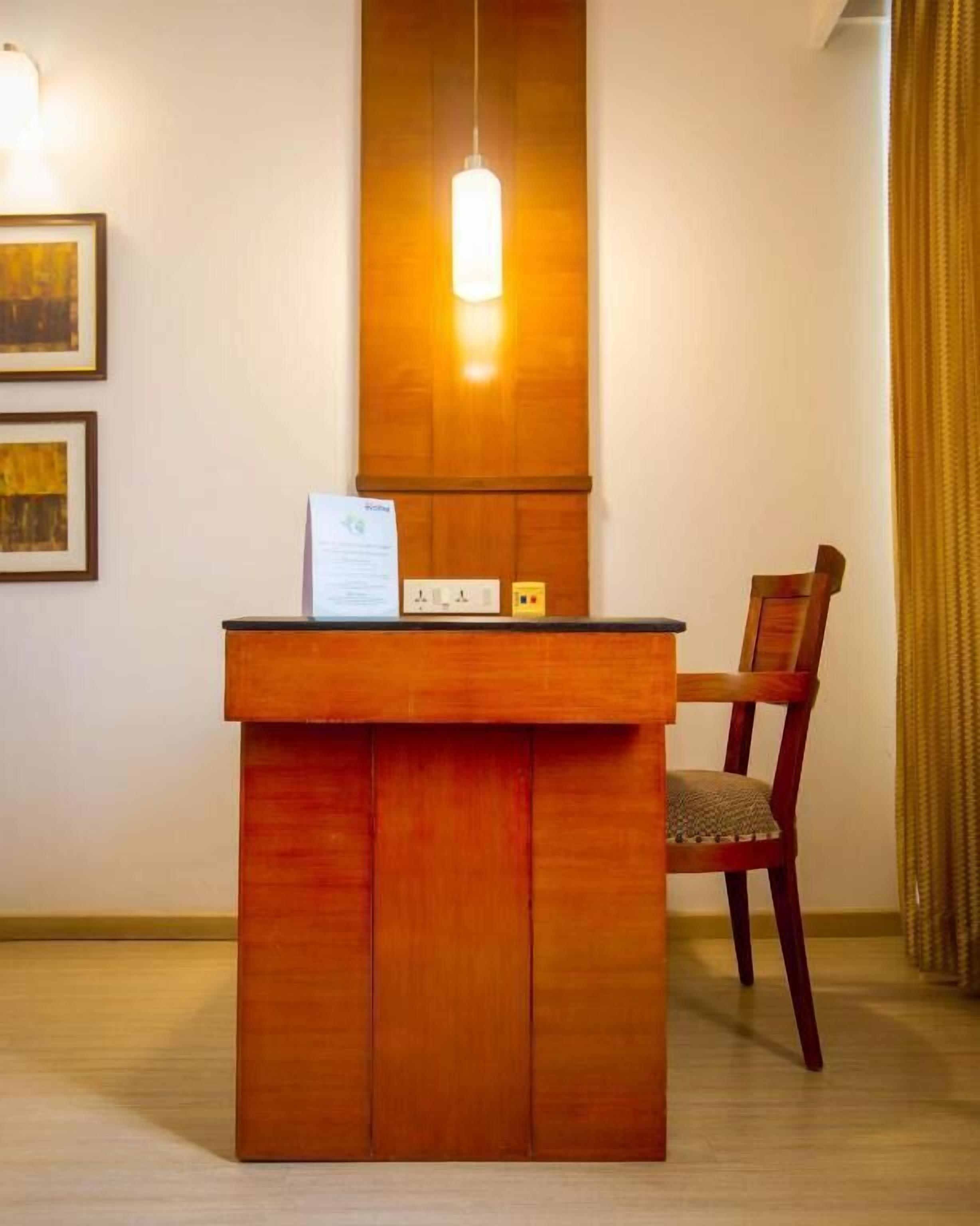 Un mostrador de recepción de madera con un cartel, una silla y una lámpara colgante.