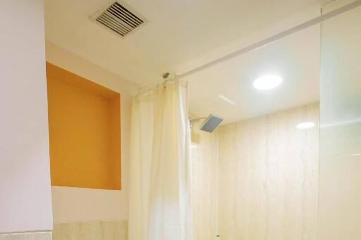 Un baño pequeño con inodoro, ducha y zona de ducha con mampara de vidrio.