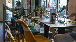 A modern dining area with a glass partition, wooden chairs, and a Christmas tree. - Celenya Hôtel (Toulon)