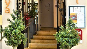 A hotel entrance with a staircase leading to the interior, potted plants at the entrance, and a sign with the hotel's name. - Celenya Hôtel (Toulon)