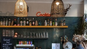 A bar area with two stools, a shelf with bottles, a globe, and a sign with text. - Celenya Hôtel (Toulon)