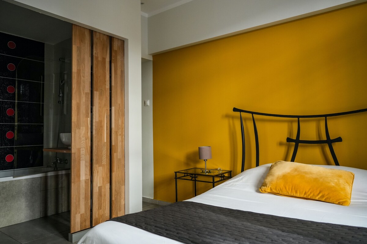 A modern bedroom with a bed, a nightstand, a lamp, and a wooden partition.
