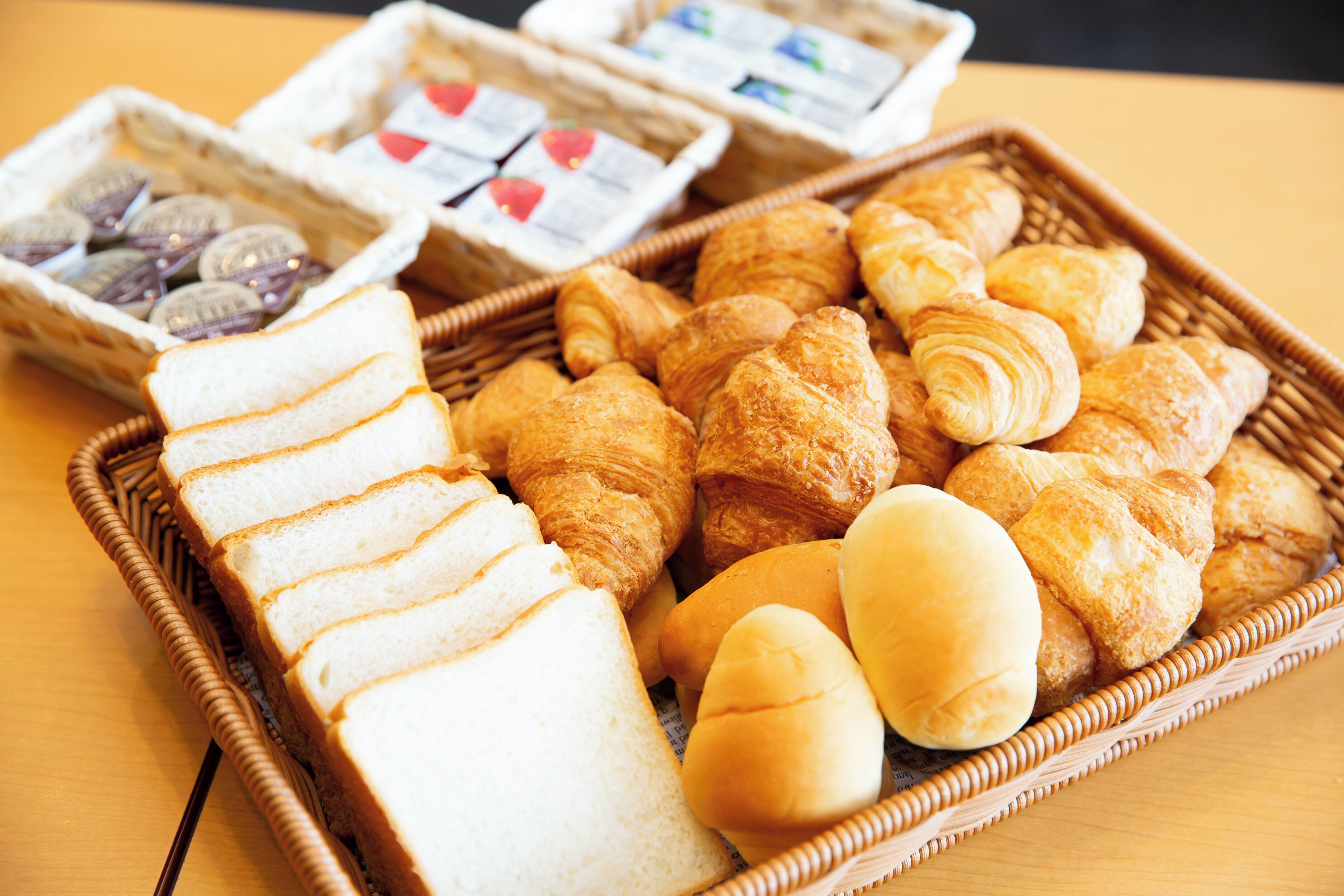 A wicker basket filled with various pastries and bread slices.