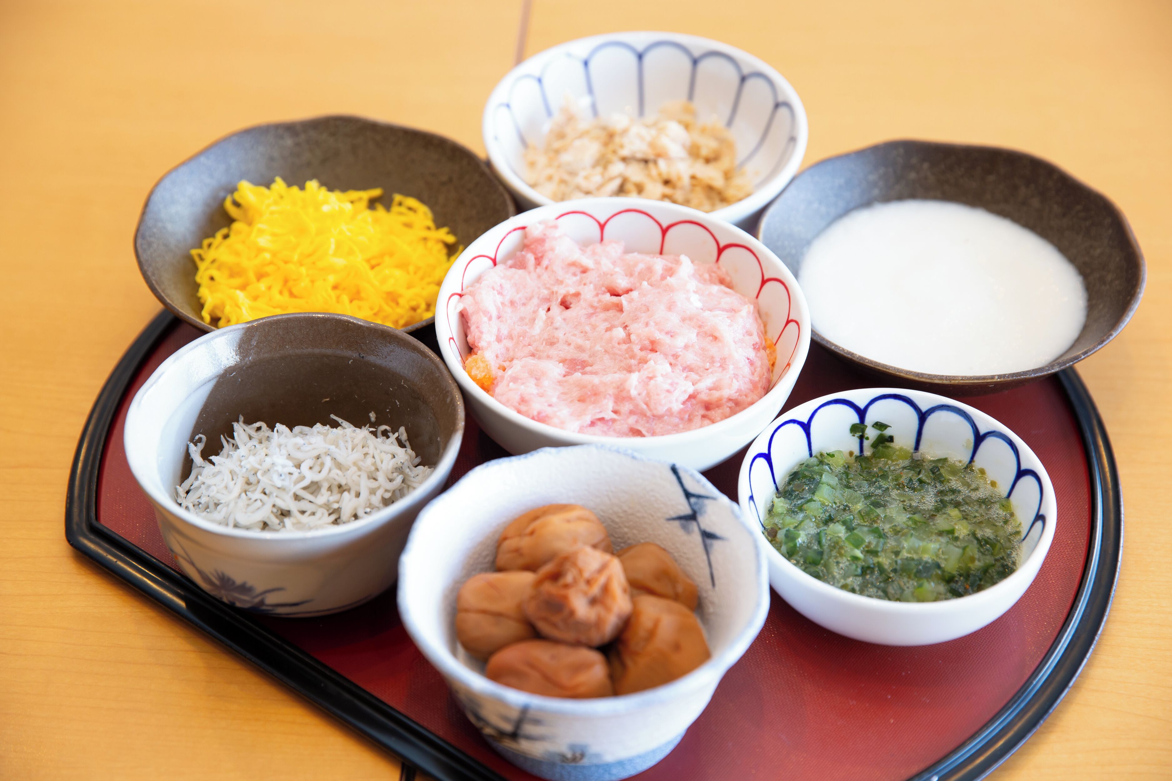A tray with various food items including shredded vegetables, a bowl of rice, and a bowl of soup.