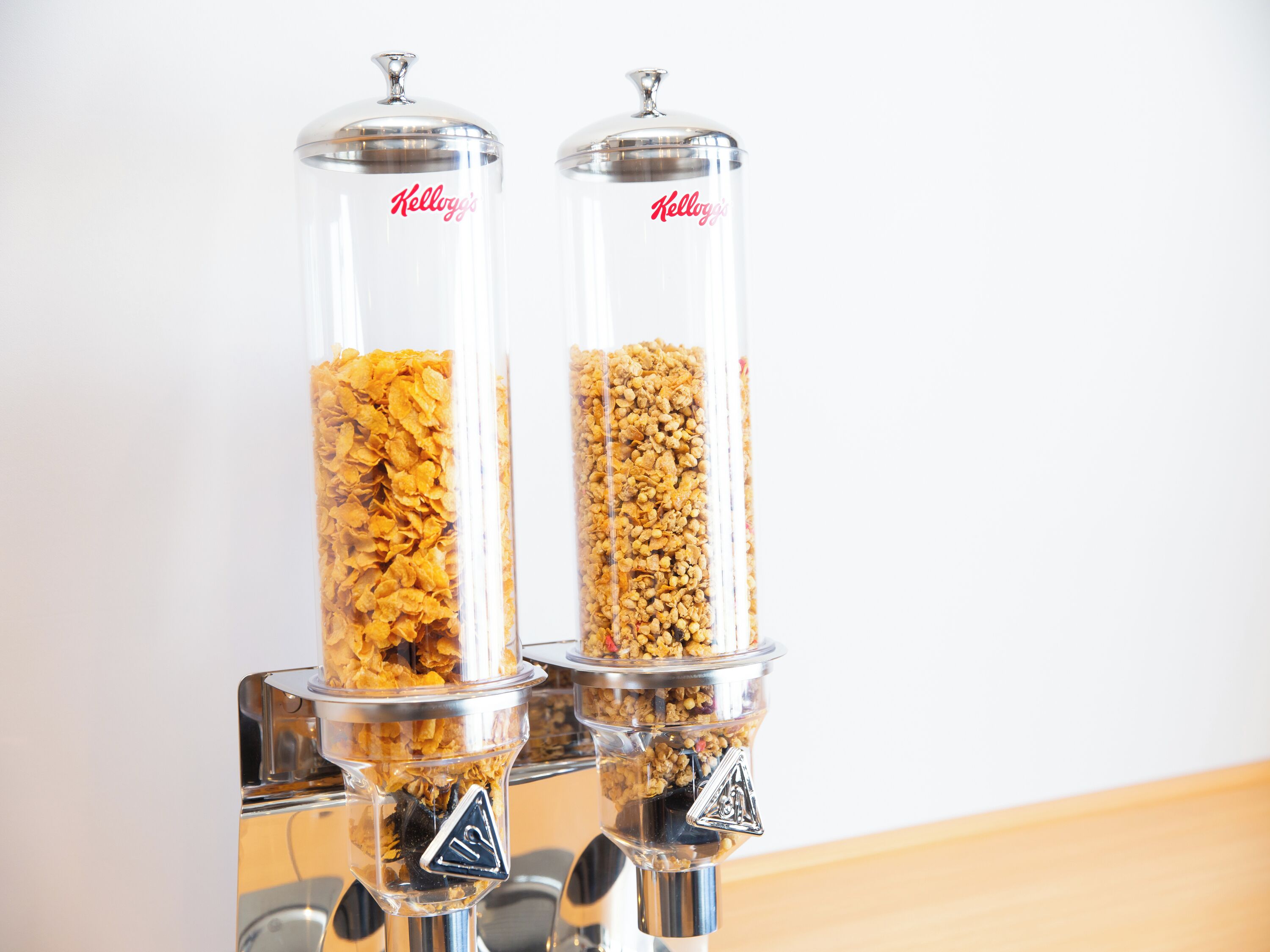 Two clear glass containers with metal lids, labeled 'Kellogg's', filled with different types of cereal flakes.