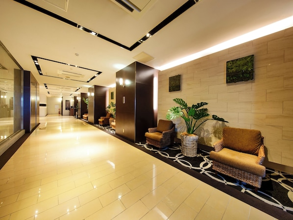 A modern hotel lobby with a long corridor, seating areas, and a reception desk.