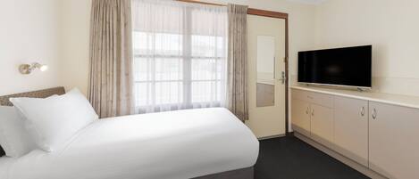 A hotel room with a bed, a television, a wardrobe, and a window with curtains.