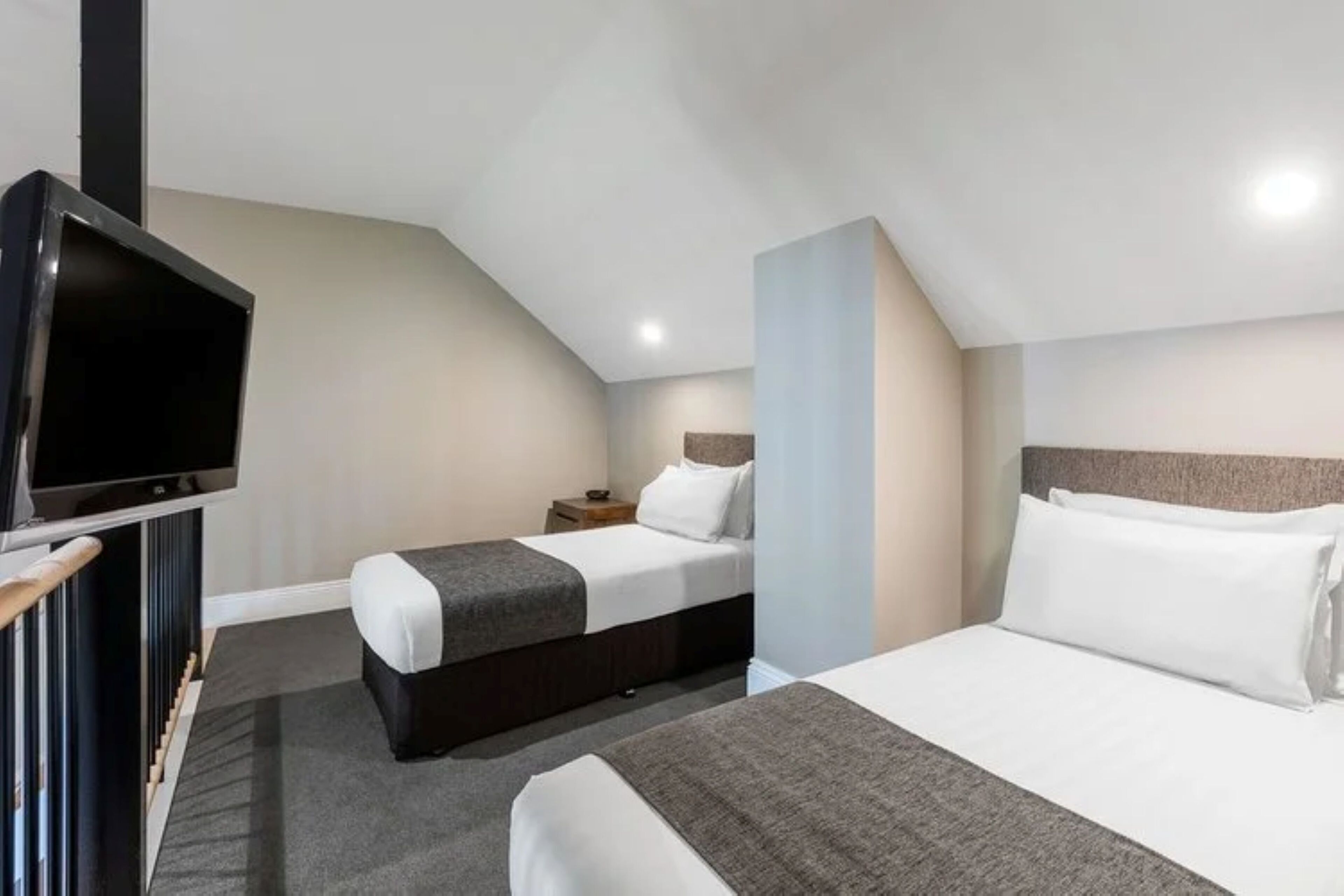 A hotel room with two beds, a TV, and a small bedside table.