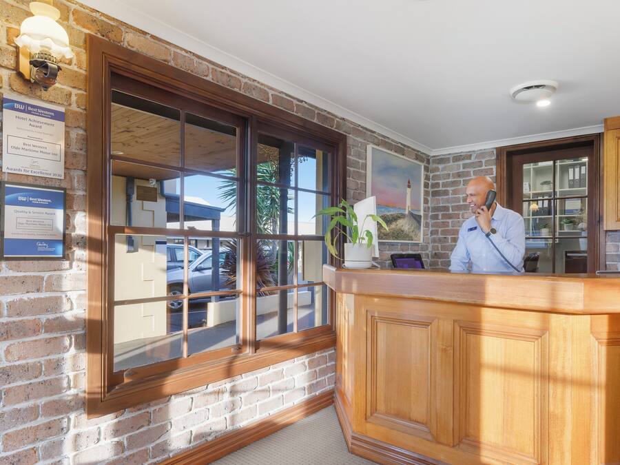 A reception desk with a wooden finish, a large window with multiple panes, and a view of the outside.