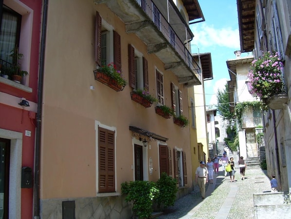 A narrow street with buildings featuring balconies and flower boxes.