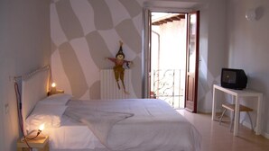 Een slaapkamer met een bed, een klein tafeltje met een televisie en een decoratief object aan de muur.