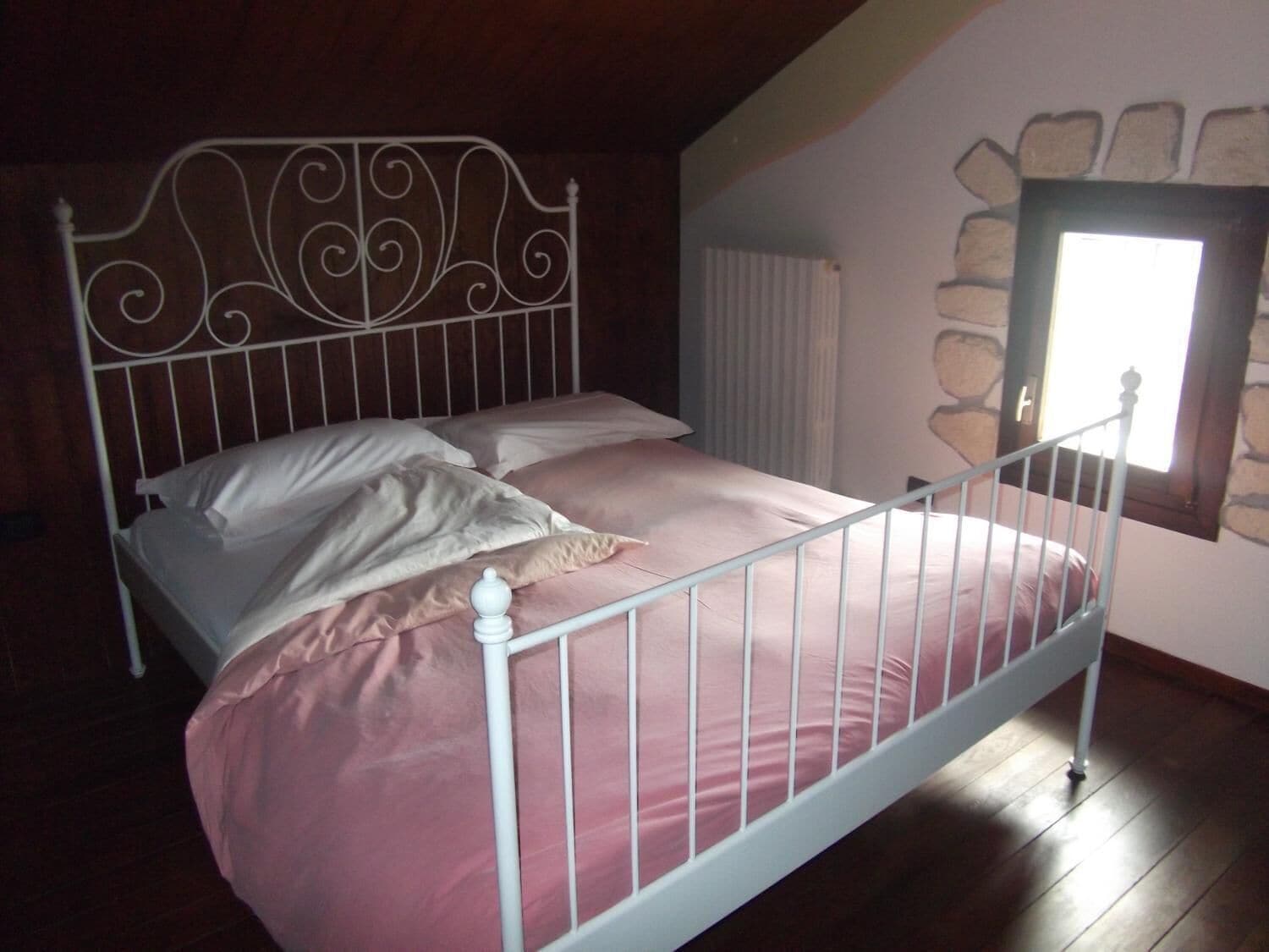Ein Bett mit Metallgestell und Steinwand.
