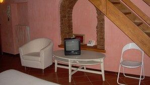 Een kamer met een witte stoel, een klein rond tafeltje en een wit opklapbaar stoeltje.