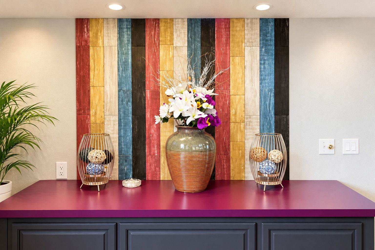A kitchen counter with a colorful wooden panel wall, a vase with flowers, and two decorative glass vases.