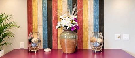 A kitchen counter with a colorful wooden panel wall, a vase with flowers, and two decorative glass vases.