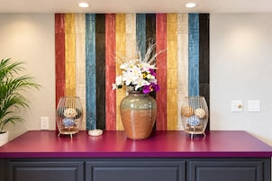 A kitchen counter with a colorful wooden panel wall, a vase with flowers, and two decorative glass vases.