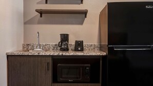 A compact kitchen with a built-in microwave, a coffee maker, and a refrigerator. - Crestview Inn (Branson West)