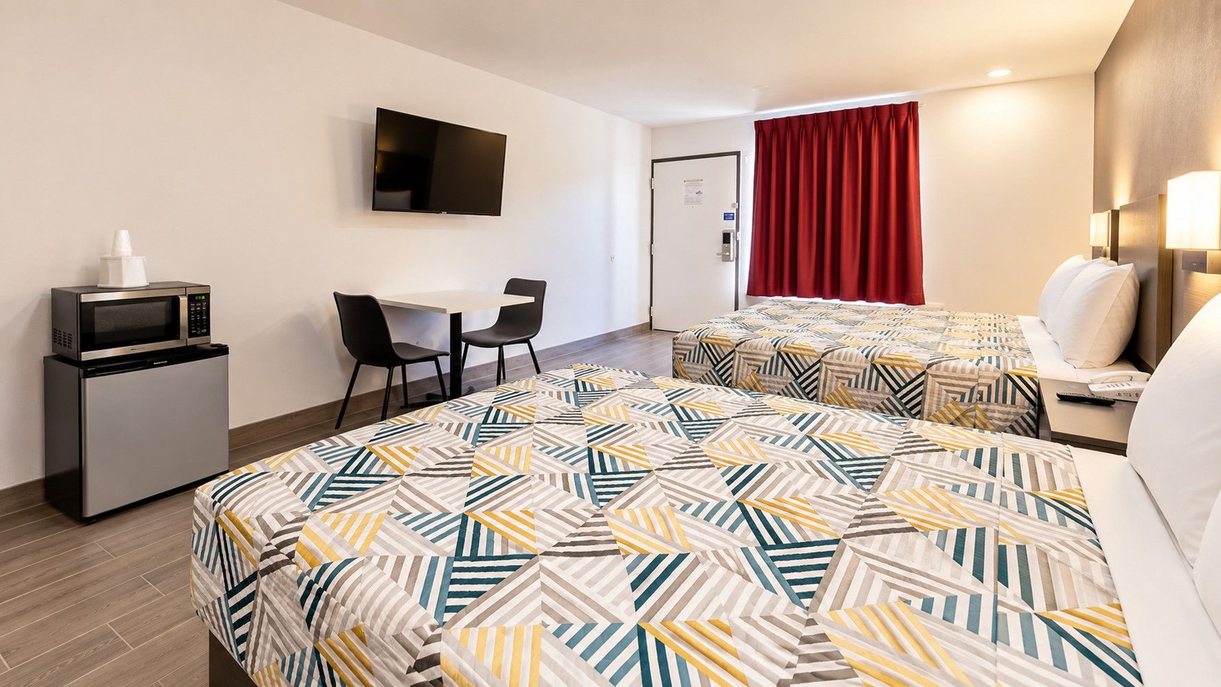 A hotel room with a bed, a desk, a TV, and a microwave.