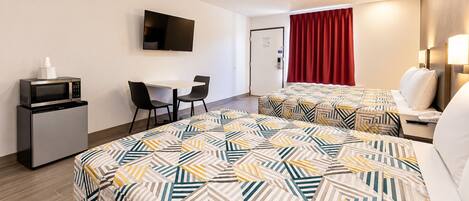 Una habitación de hotel con una cama, un escritorio, un televisor y un microondas.