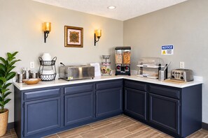Una kitchenette equipada con tostadora, cafetera y dispensador de bebidas.
