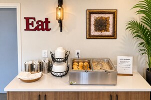 A breakfast buffet setup with plates, utensils, and a sign.