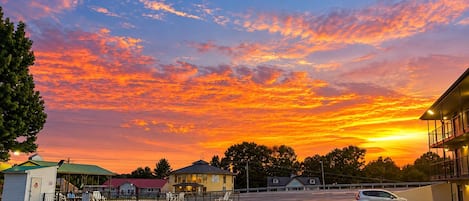 Un estacionamiento con edificios, cielo despejado y atardecer.