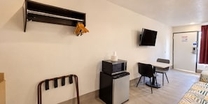 A hotel room with a kitchenette, a flat-screen TV mounted on the wall, a small table with chairs, and a bed with patterned bedding. - Crestview Inn Branson West by Silver Dollar City (Branson West)