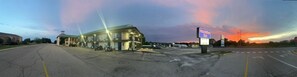 Un motel avec un grand parking, un panneau de signalisation et un coucher de soleil en arrière-plan.