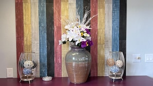 A room with a striped wall, a large vase with flowers, and two decorative vases on a table. - Crestview Inn (Branson West)